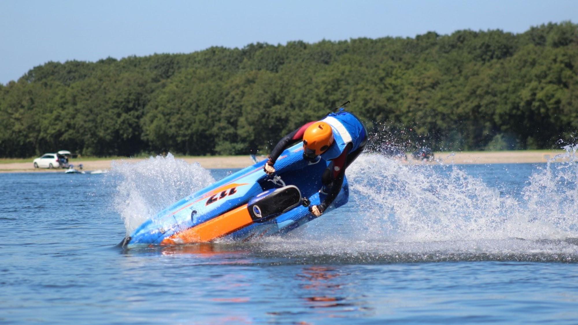 Eine junge Frau macht einen Trick auf ihrem Jet-Ski auf dem See.