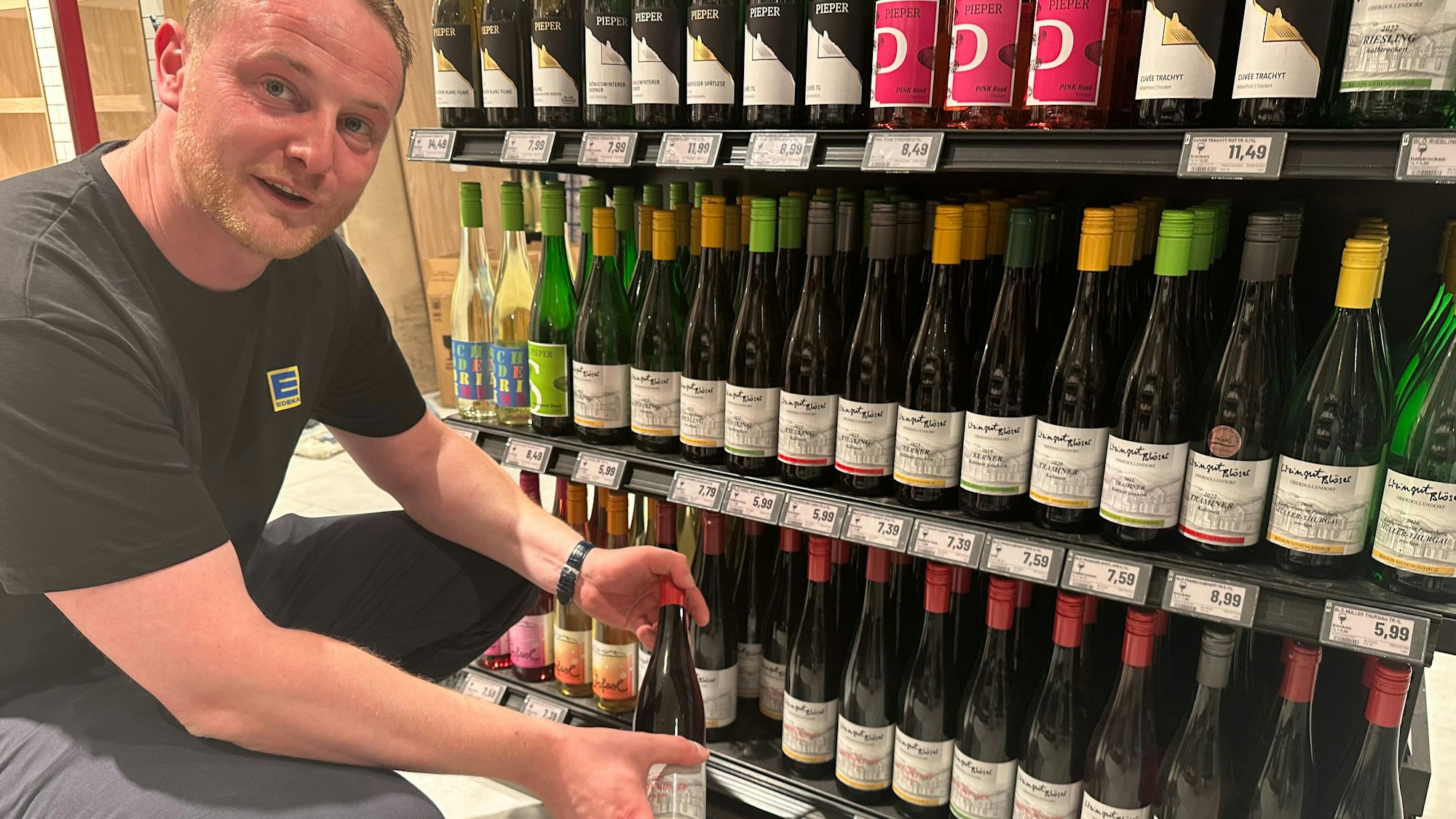Edeka-Kaufmann Severin Hemmersbach an der Weintheke mit Weinen aus dem Siebengebirge der Winzer Pieper und Blöser.