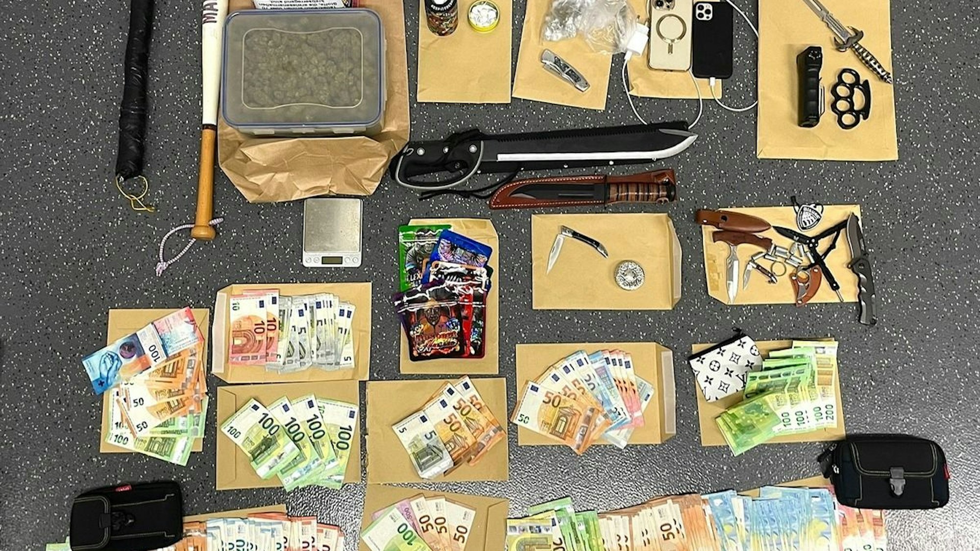 Sichergestellte Waffen, Drogen und Bargeld liegen auf einem Tisch.