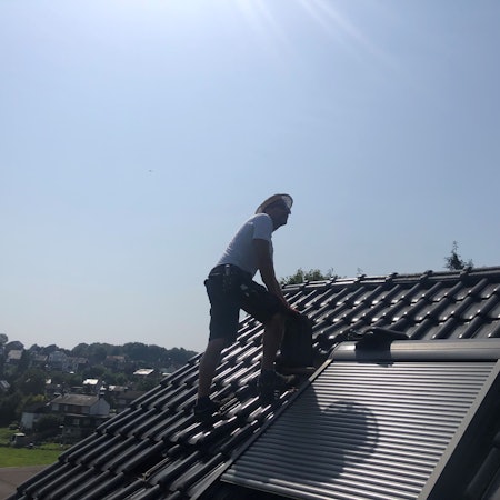 Ein Dachdecker steht auf einem Dach.