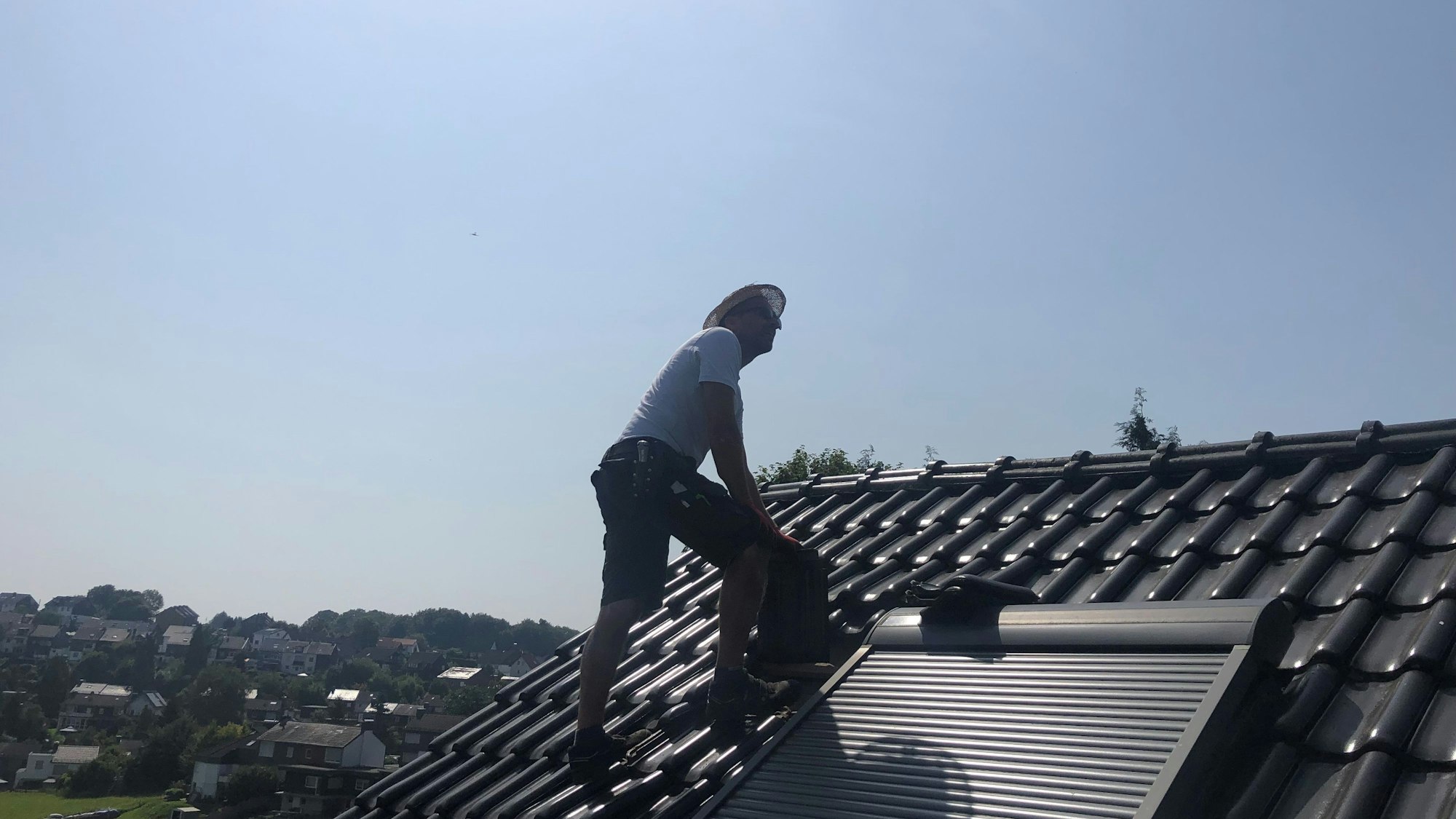 Ein Dachdecker steht auf einem Dach.