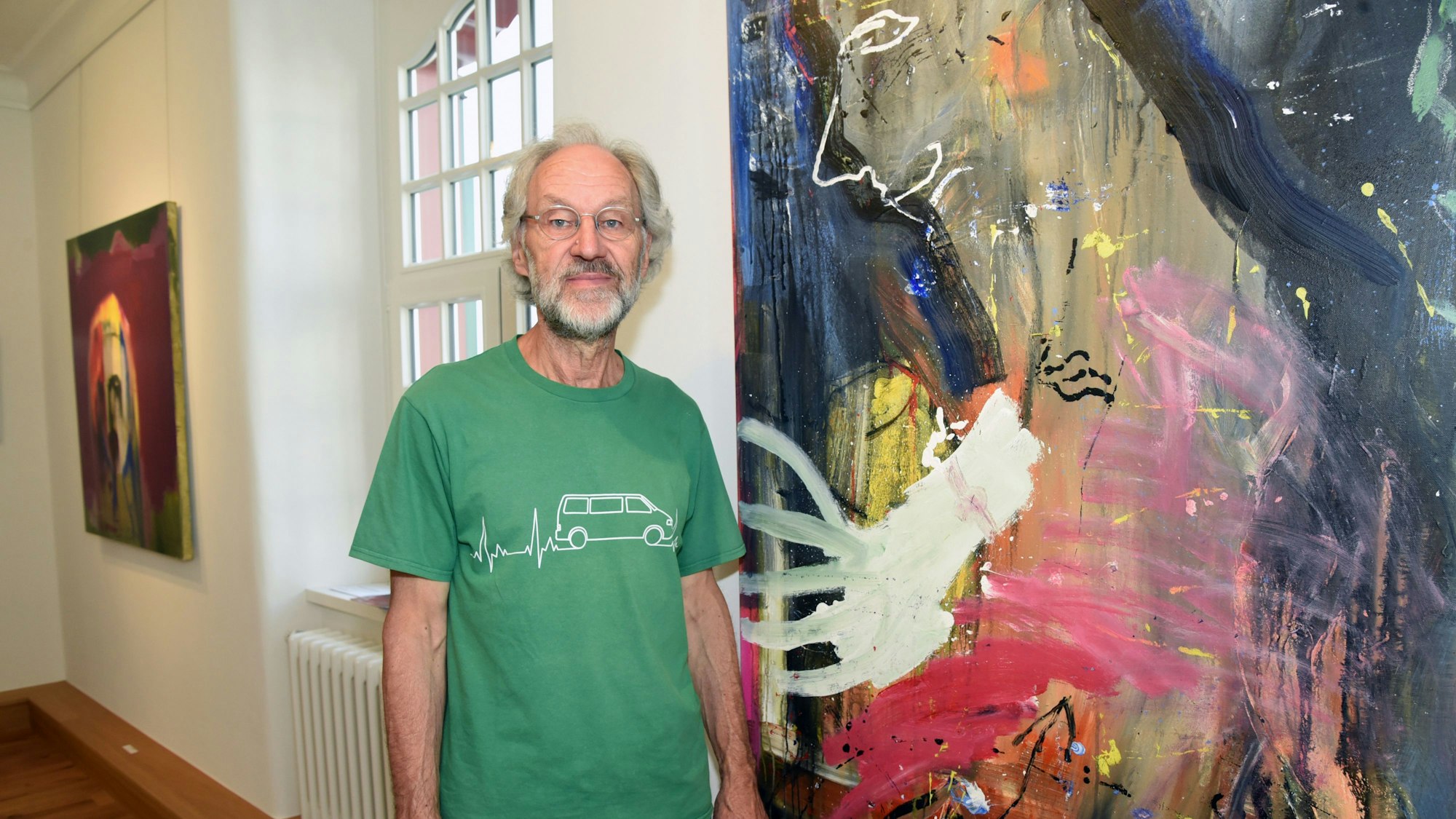 Das Foto zeigt den Maler Bruno Obermann neben einem seiner abstrakten Bilder.