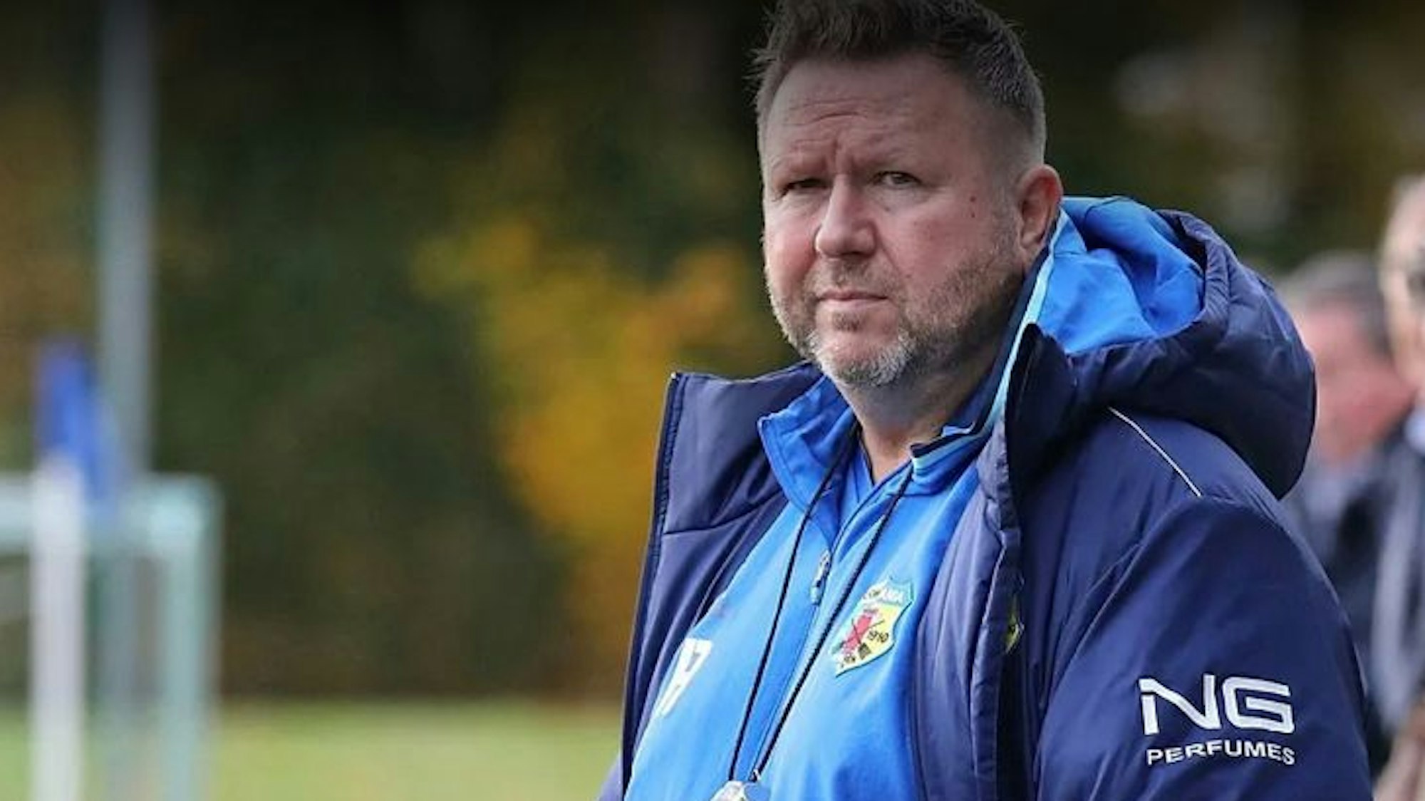 Das Foto zeigt einen Fußballtrainer an der Seitenlinie, die Augen auf das Spiel seiner Elf gerichtet.