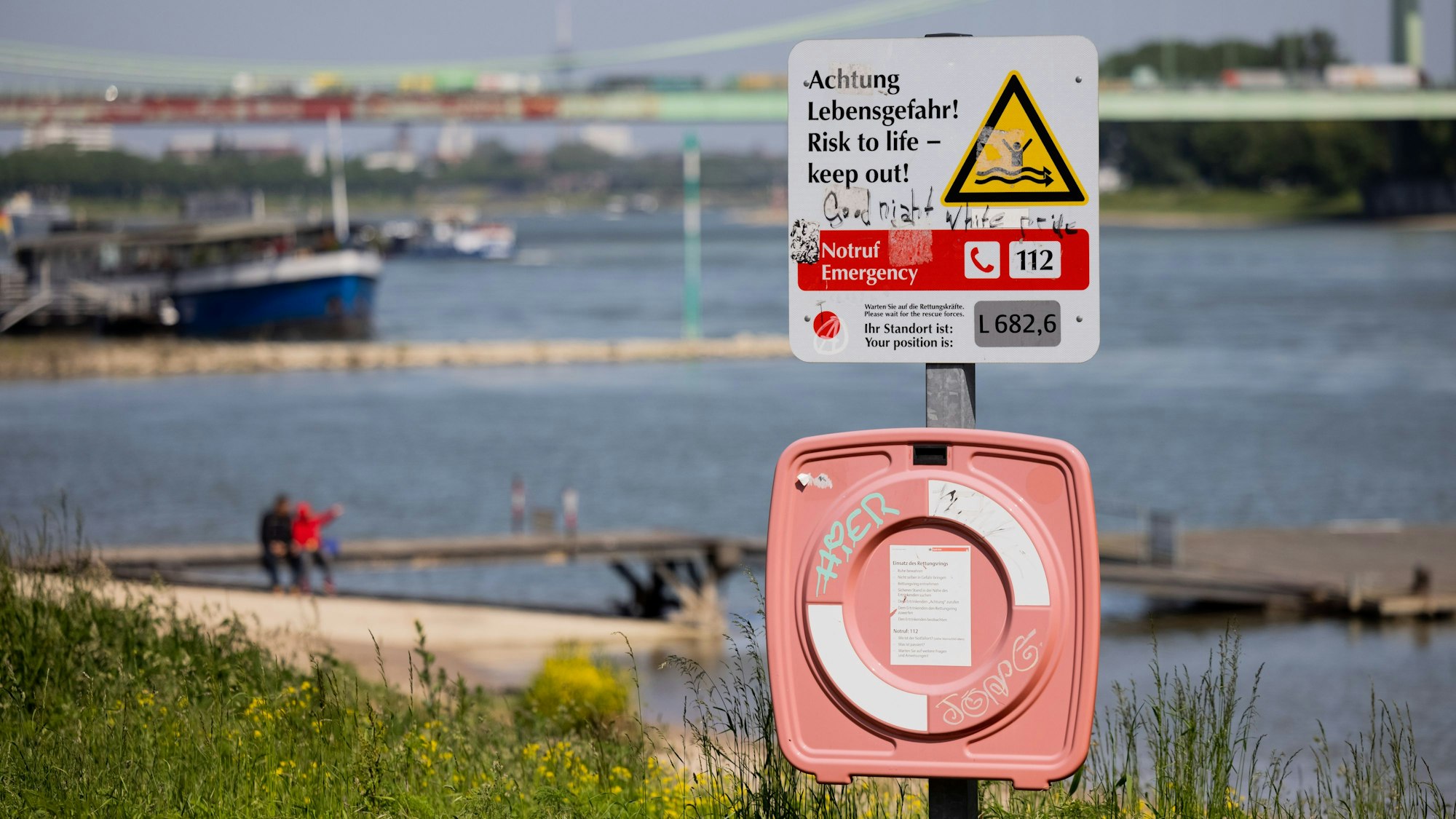 Ein Hinweisschild mit der Aufschrift „Achtung Lebensgefahr“ weist am Rhein in Köln-Rodenkirchen auf die Gefahren beim Schwimmen in dem Fluss hin.