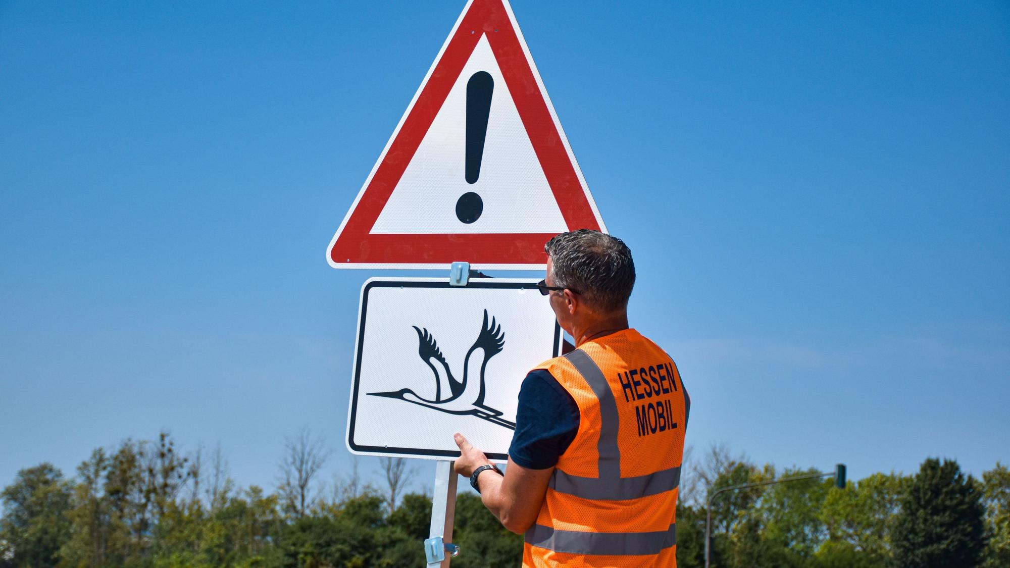 Ein Warnschild vor tieffliegenden Störchen wird in Wabern im Schwalm-Eder-Kreis montiert.