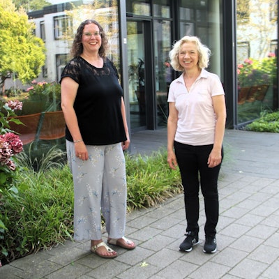 Zwei Frauen stehen vor einem Glas-Eingang