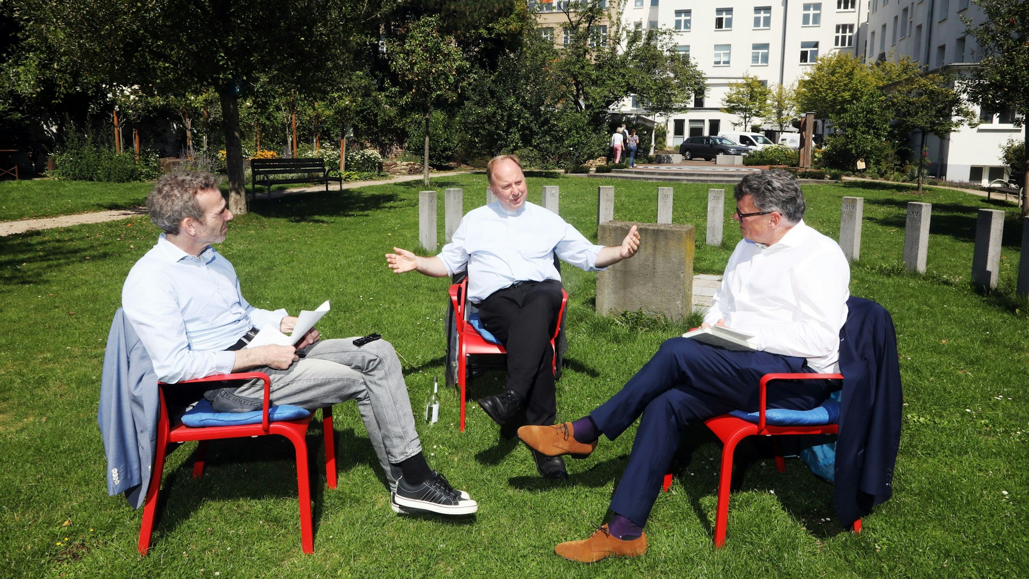 07.08.2025, Köln: Gerald Selch und Joachim Frank mit Stadtdechant Robert Kleine im Garten der Religionen. Foto: Arton Krasniqi