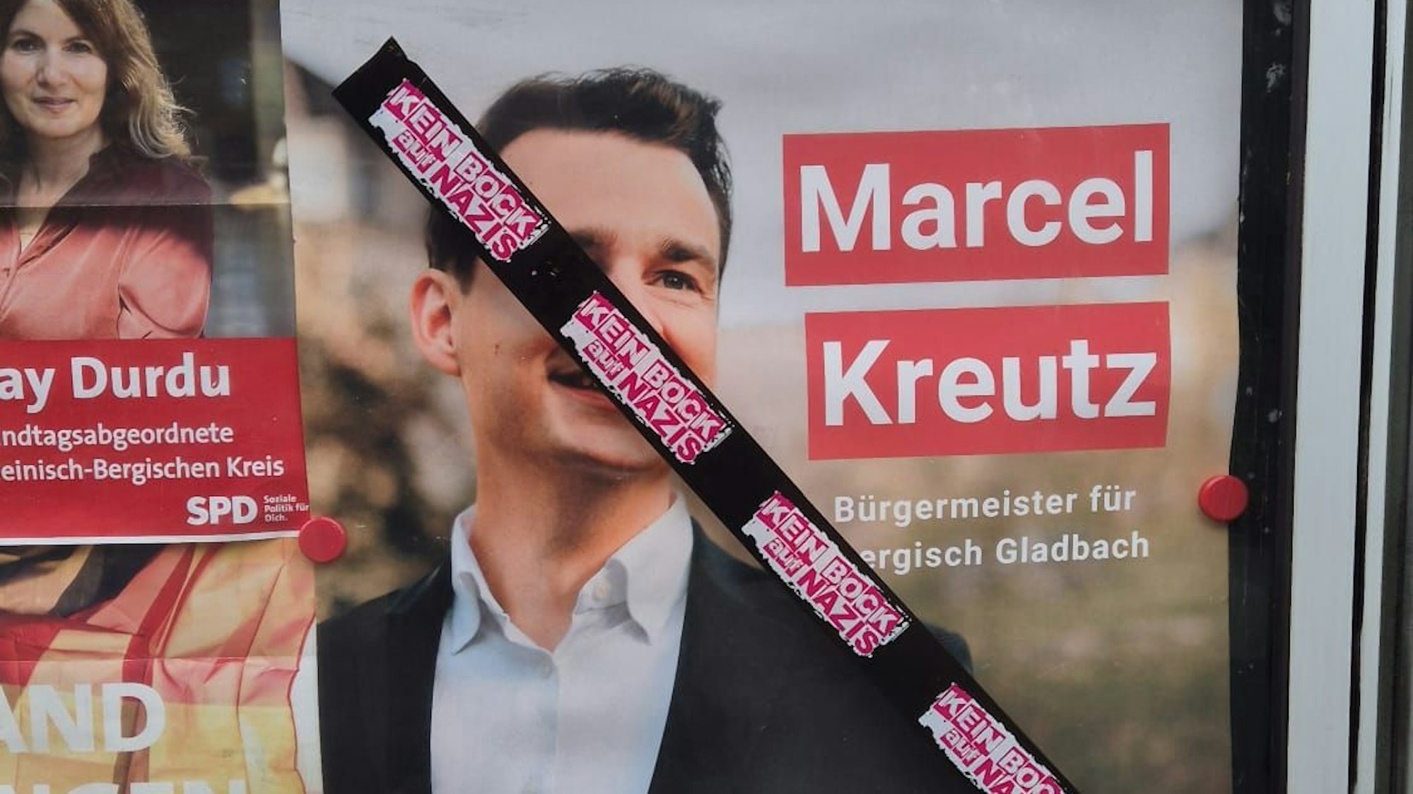 Auf einem Schaukasten der SPD in Refrath mit einem Plakat von SPD/Grünen-Bürgermeisterkandidat Marcel Kreutz prangt eine Reihe von Aufklebern mit der Aufschrift „Kein Bock auf Nazis“.