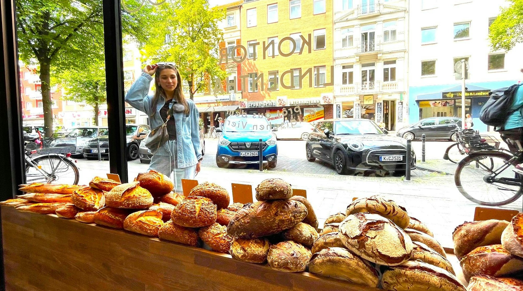 Eine junge Frau steht vor dem Schaufenster einer Bäckerei.