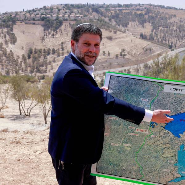 Bezalel Smotrich zeigt lächelnd auf eine Karte.