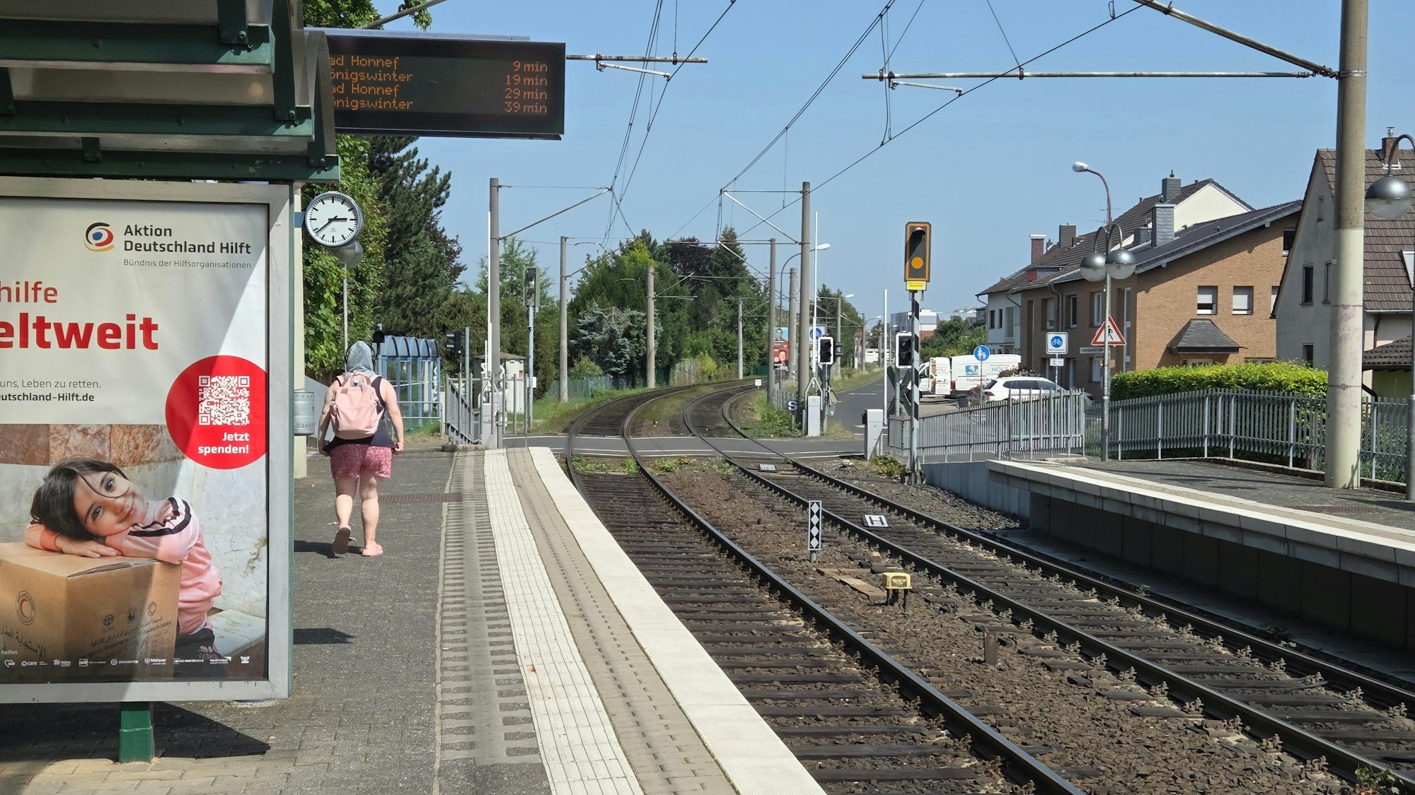 Wenig Schatten findet sich an der Haltestelle der 66 in Hangelar West. Eine Pendlerin schützt sich mit einem Tuch auf dem Kopf vor der knalligen Sonne.