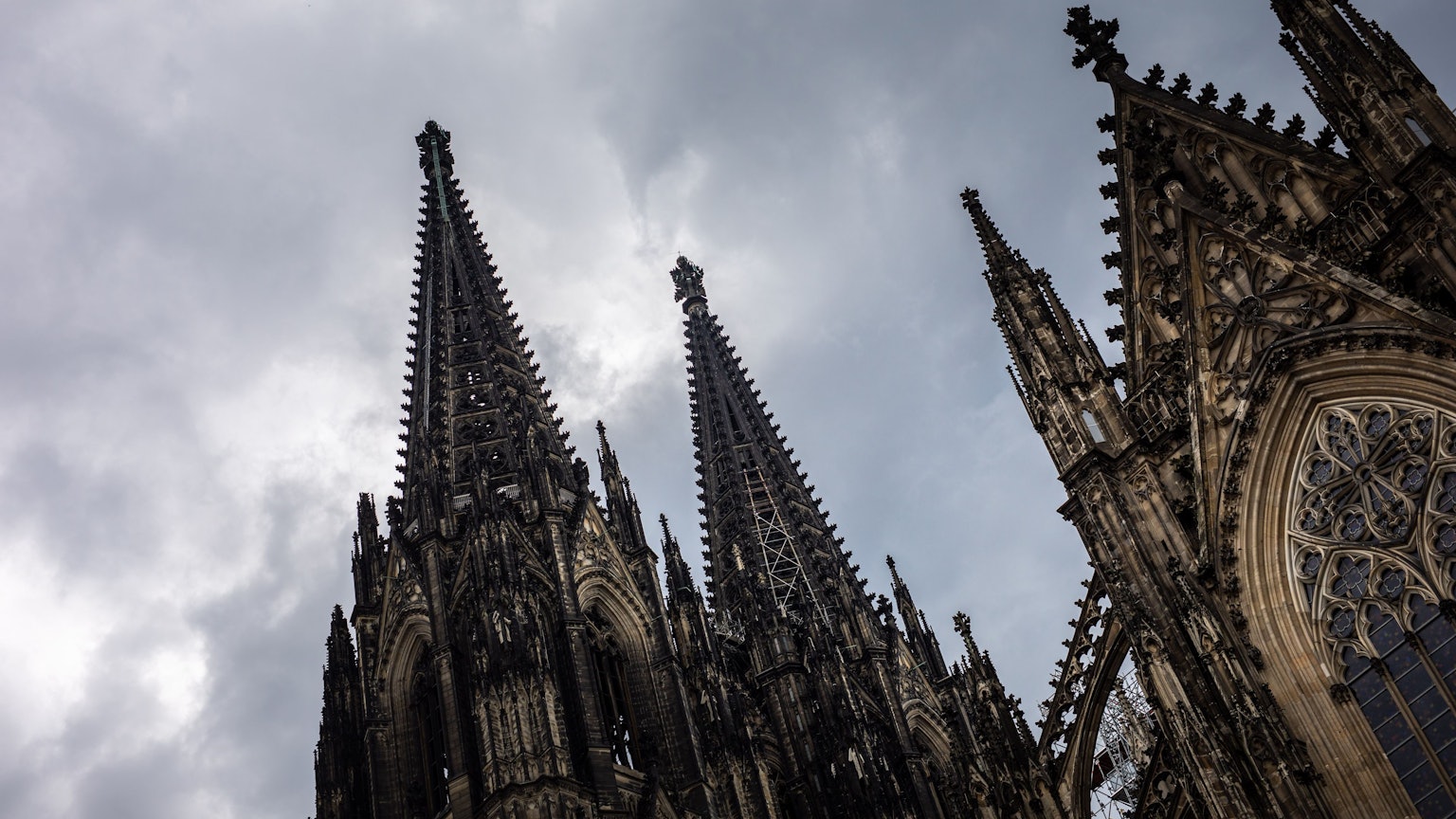 Der Kölner Dom (Hohe Domkirche St. Petrus) ist vor dunklen Wolken zu sehen.