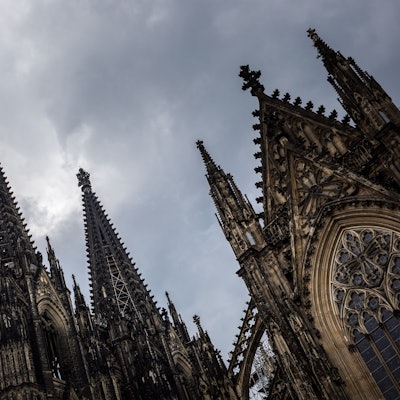 Der Kölner Dom (Hohe Domkirche St. Petrus) ist vor dunklen Wolken zu sehen.