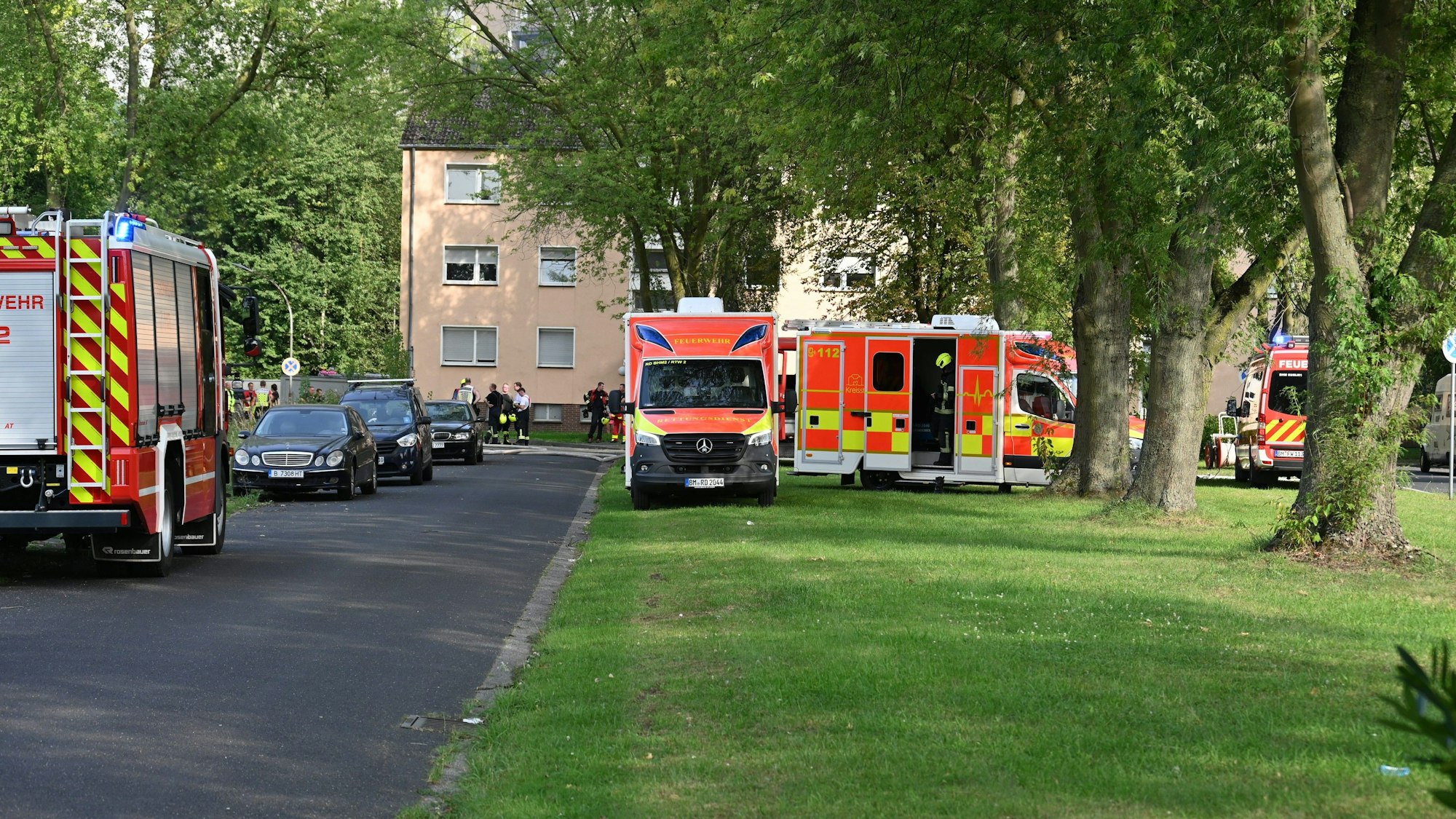 Mehrere Einsatzfahrzeuge der Feuerwehr stehen vor einem Häuserkomplex.