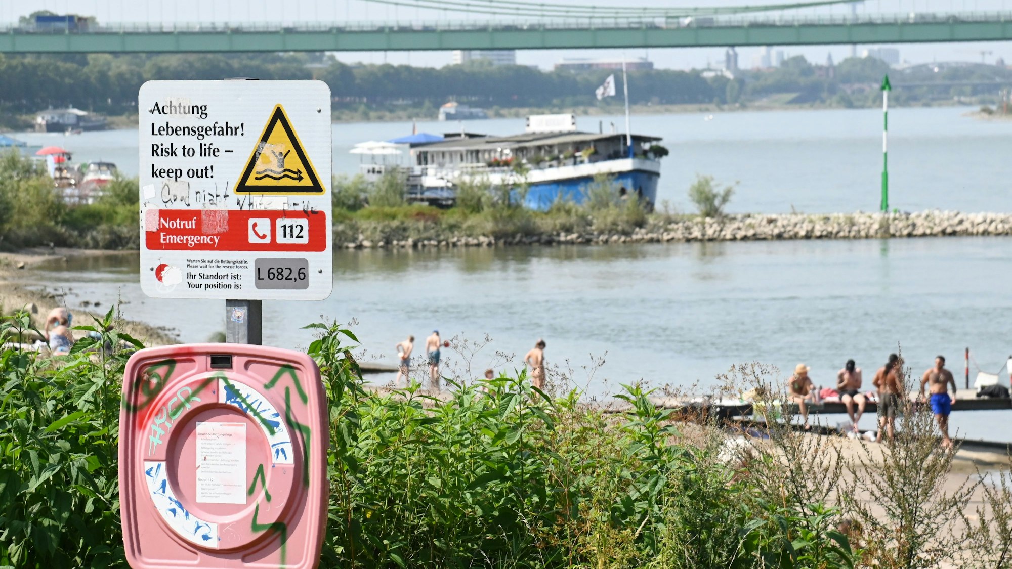 An der Rodenkirchener Riviera weist ein Schild auf die Gefahren beim Baden im Rhein hin.