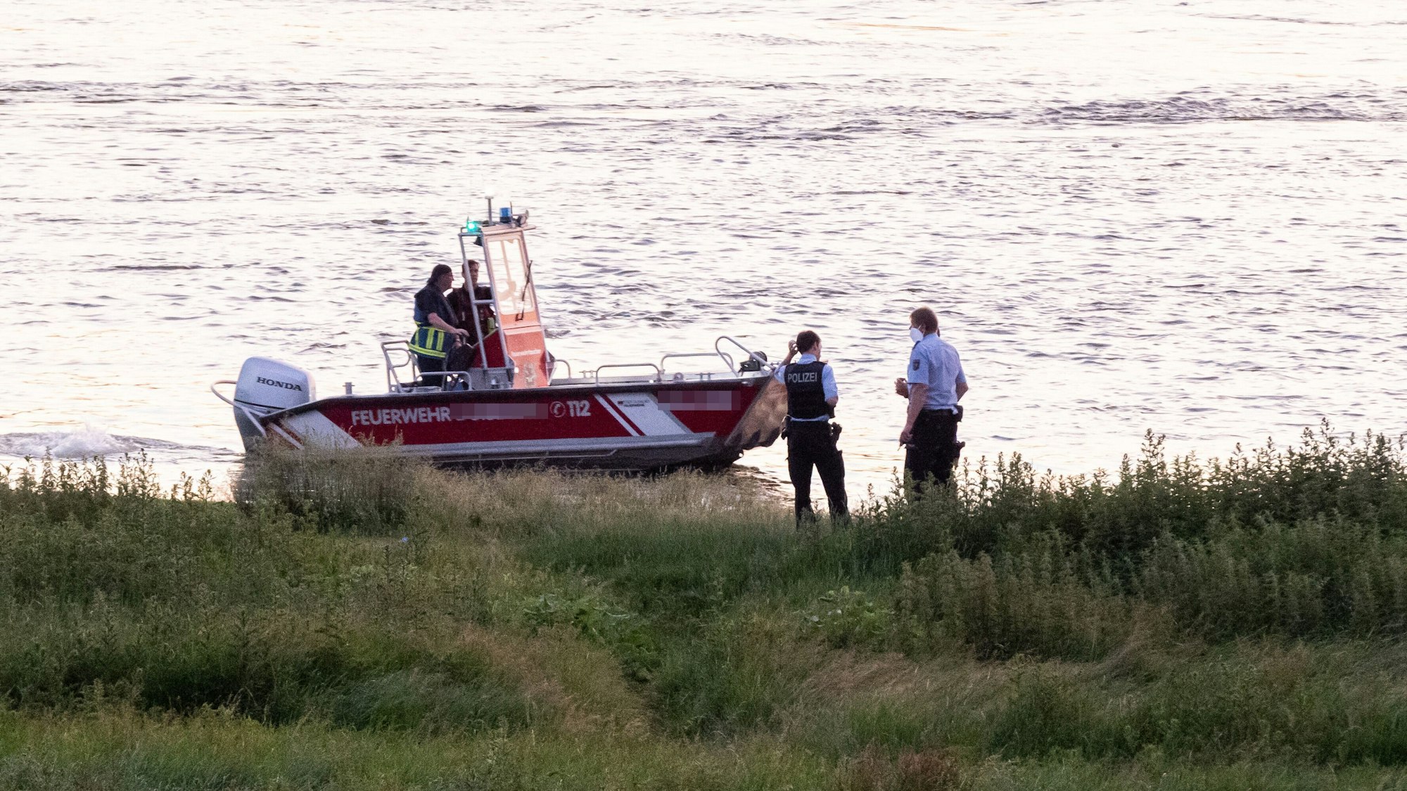 Einsatzkräfte der Polizei, Feuerwehr und DRLG am Ufer des Rheins (Symbolfoto).