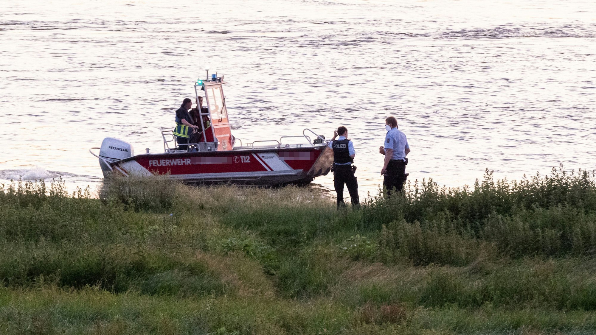 Einsatzkräfte der Polizei, Feuerwehr und DRLG arbeiten am Ufer des Rheins. (Archivfoto)