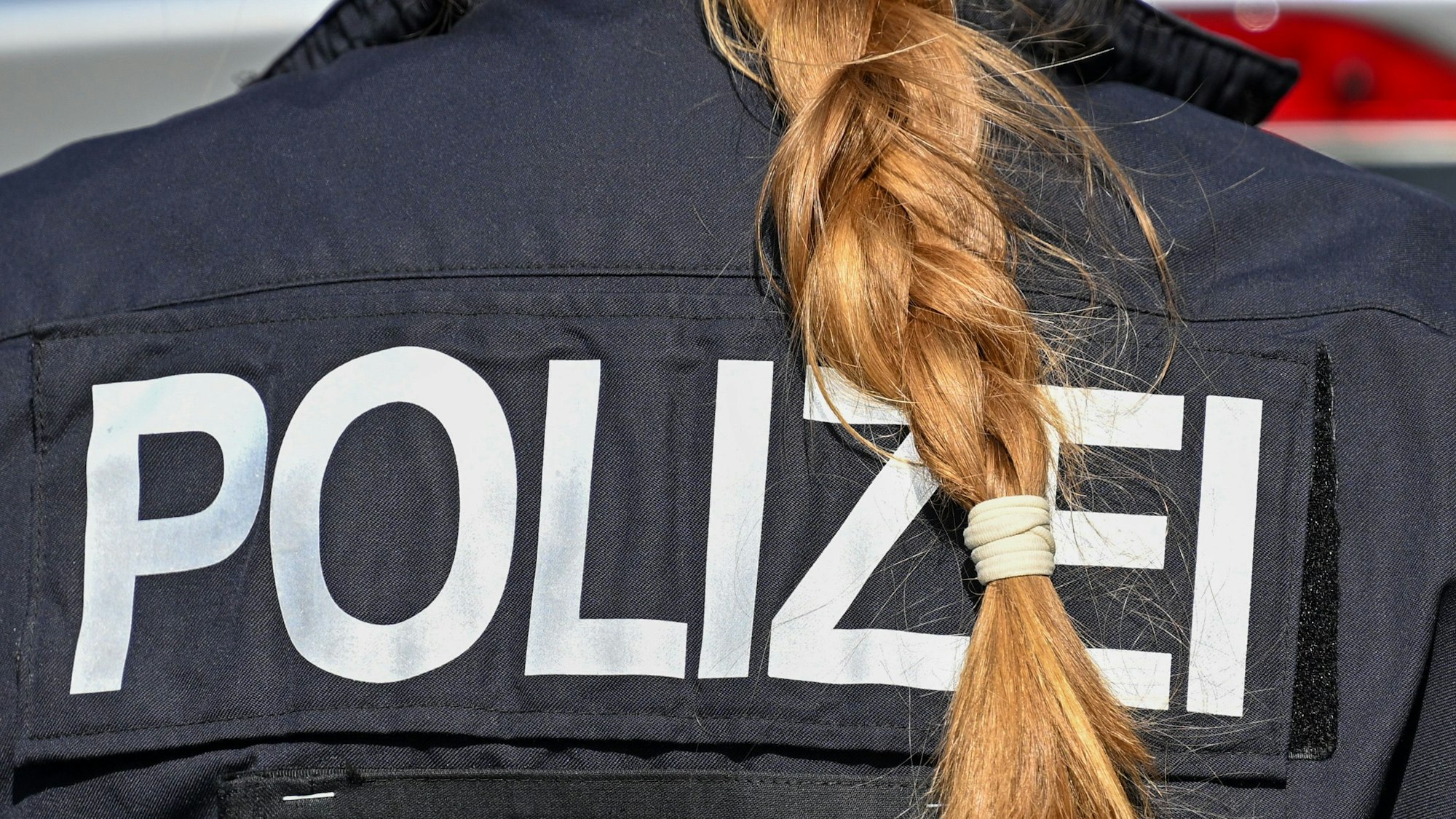 ARCHIV - 05.07.2025, Berlin: Der Zopf einer Polizistin hängt über ihre Uniform. (zu dpa: «Polizei ermittelt nach Drohung an Schule in Ermsleben») Foto: Soeren Stache/dpa +++ dpa-Bildfunk +++