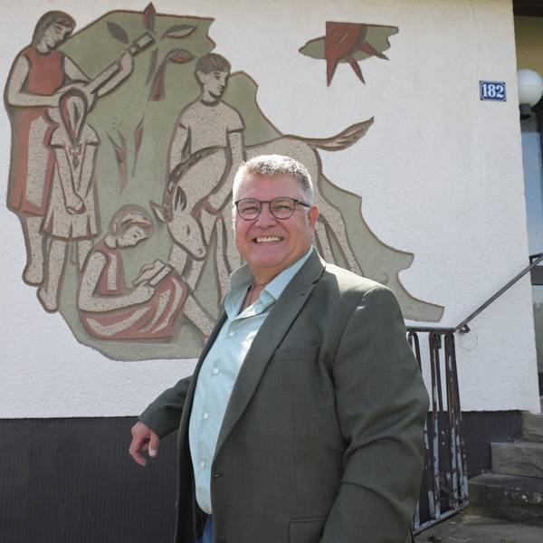 Ein Mann steht vor einer Hausfassade mit einem großen Wandbild.