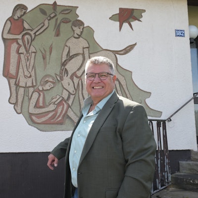 Ein Mann steht vor einer Hausfassade mit einem großen Wandbild.