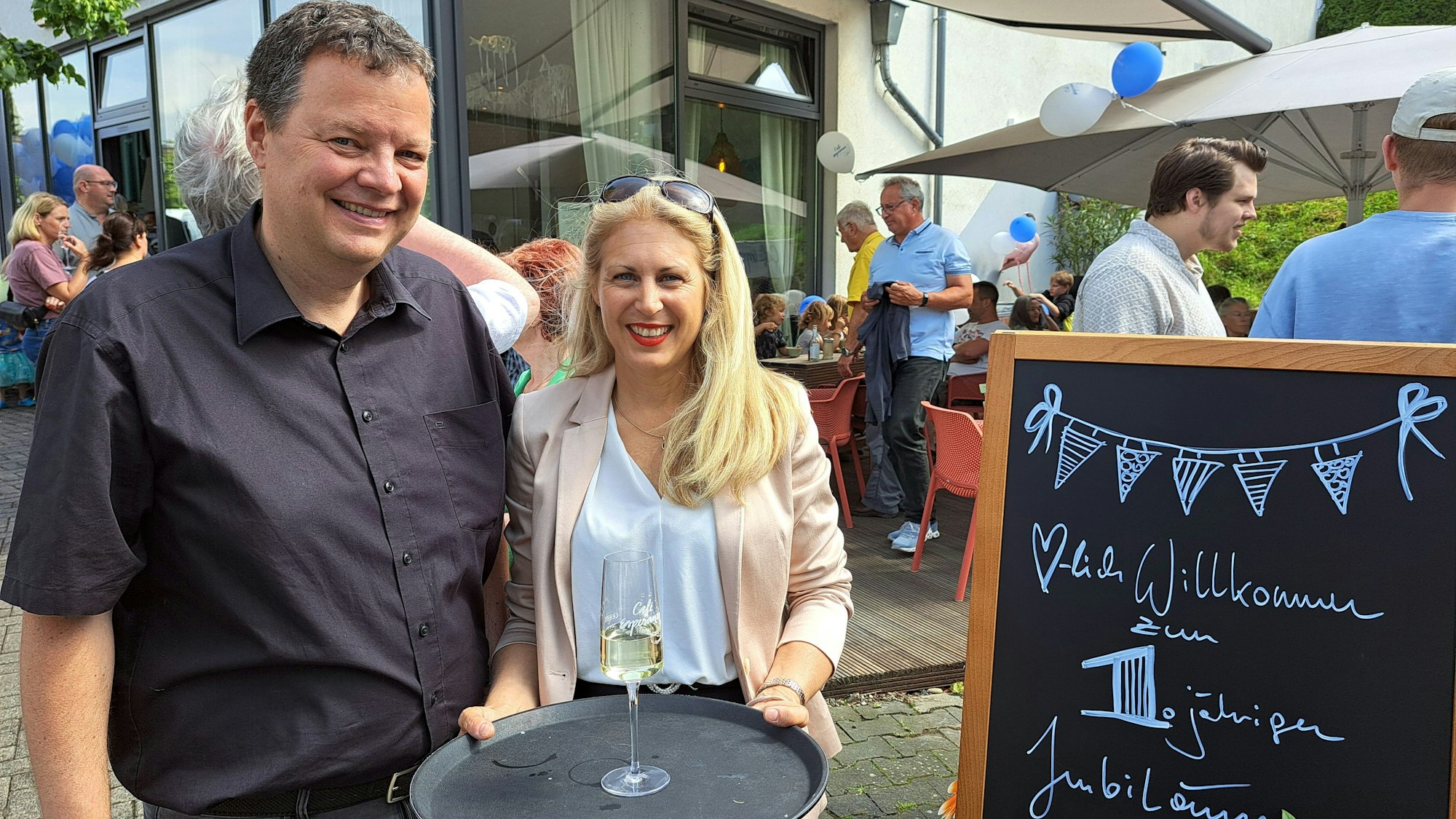Sarah und Andreas Bettermann stehen neben einer Tafel mit der Aufschrift des „einjährigen Jubiläum“ ihres Cafés Esperanza.