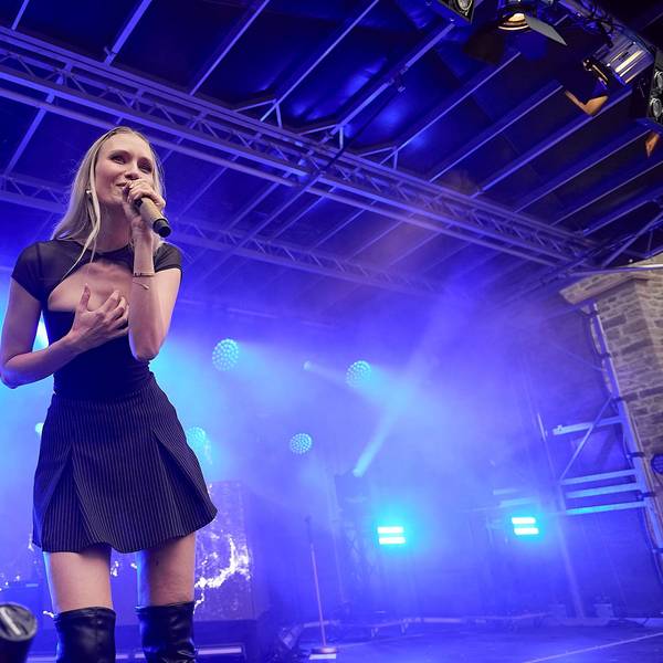 Carolin Niemczyk im kurzen, schwarzen Kleid bei ihrem Bühnenauftritt vor blauem Scheinwerferlicht.