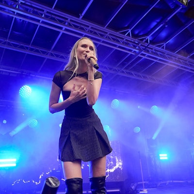 Carolin Niemczyk im kurzen, schwarzen Kleid bei ihrem Bühnenauftritt vor blauem Scheinwerferlicht.