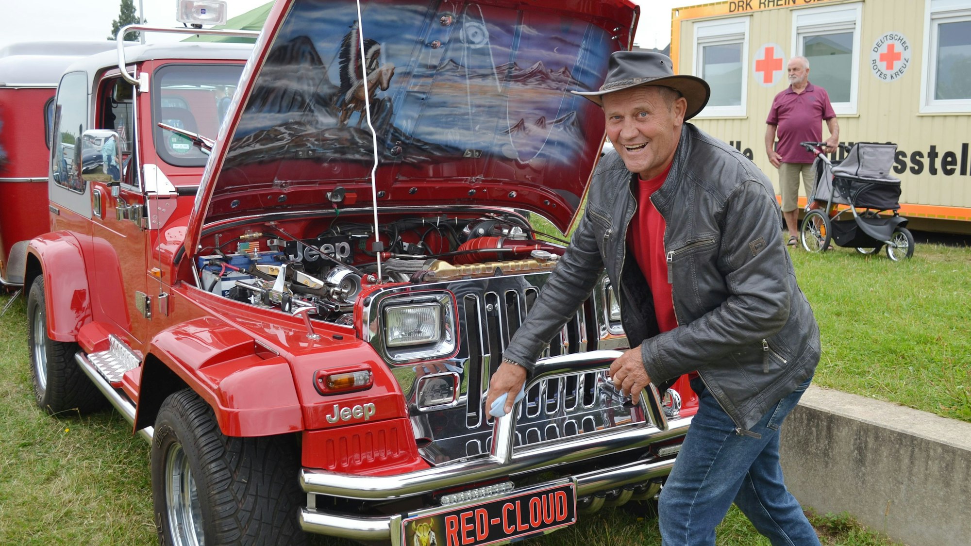 Ein Mann mit Cowboyhut vor einem Jeep mit innen lackierter Motorhaube.
