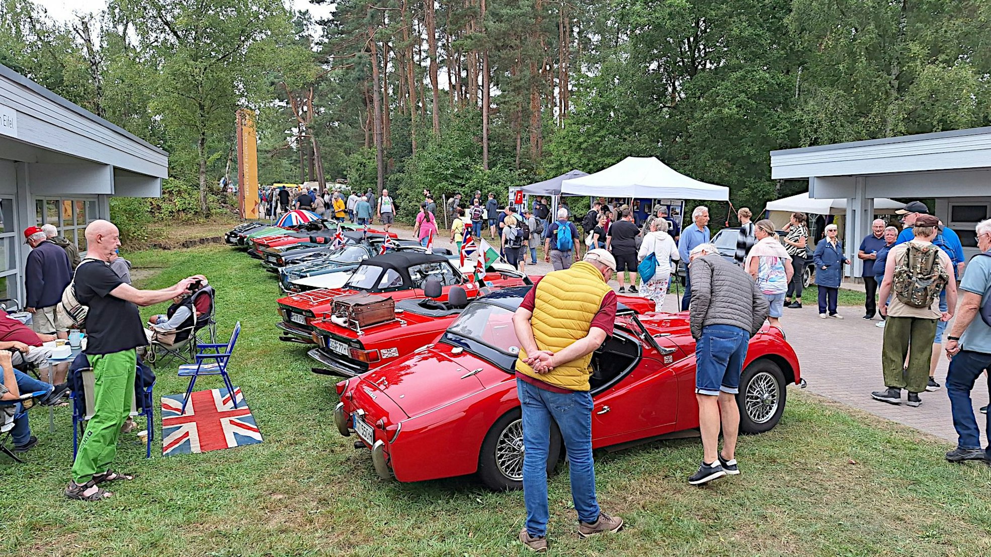 Die Roadster sind in einer Reihe geparkt. Die Besucher flanieren daran vorbei.