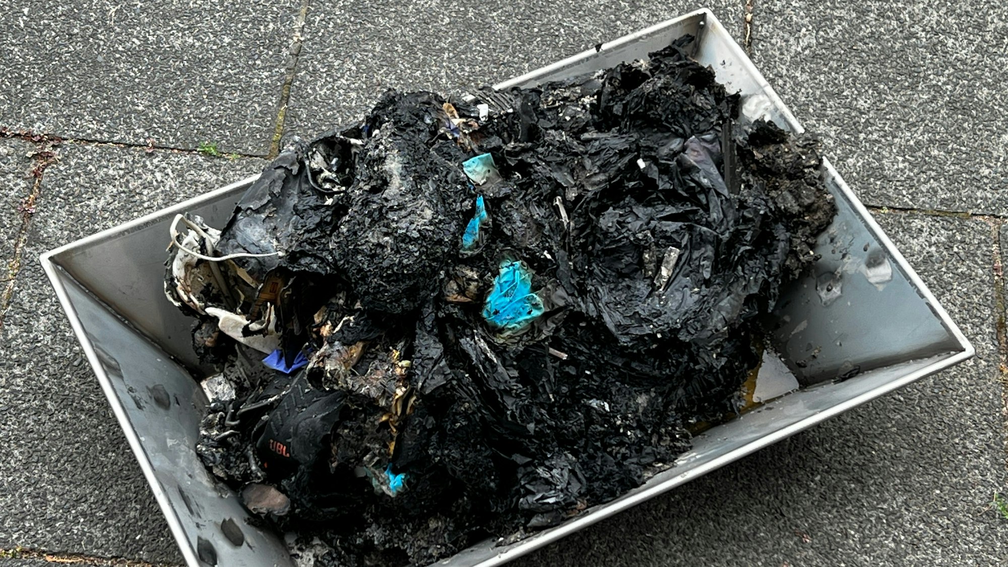 Verkohlter Abfall in einem Metallbehälter