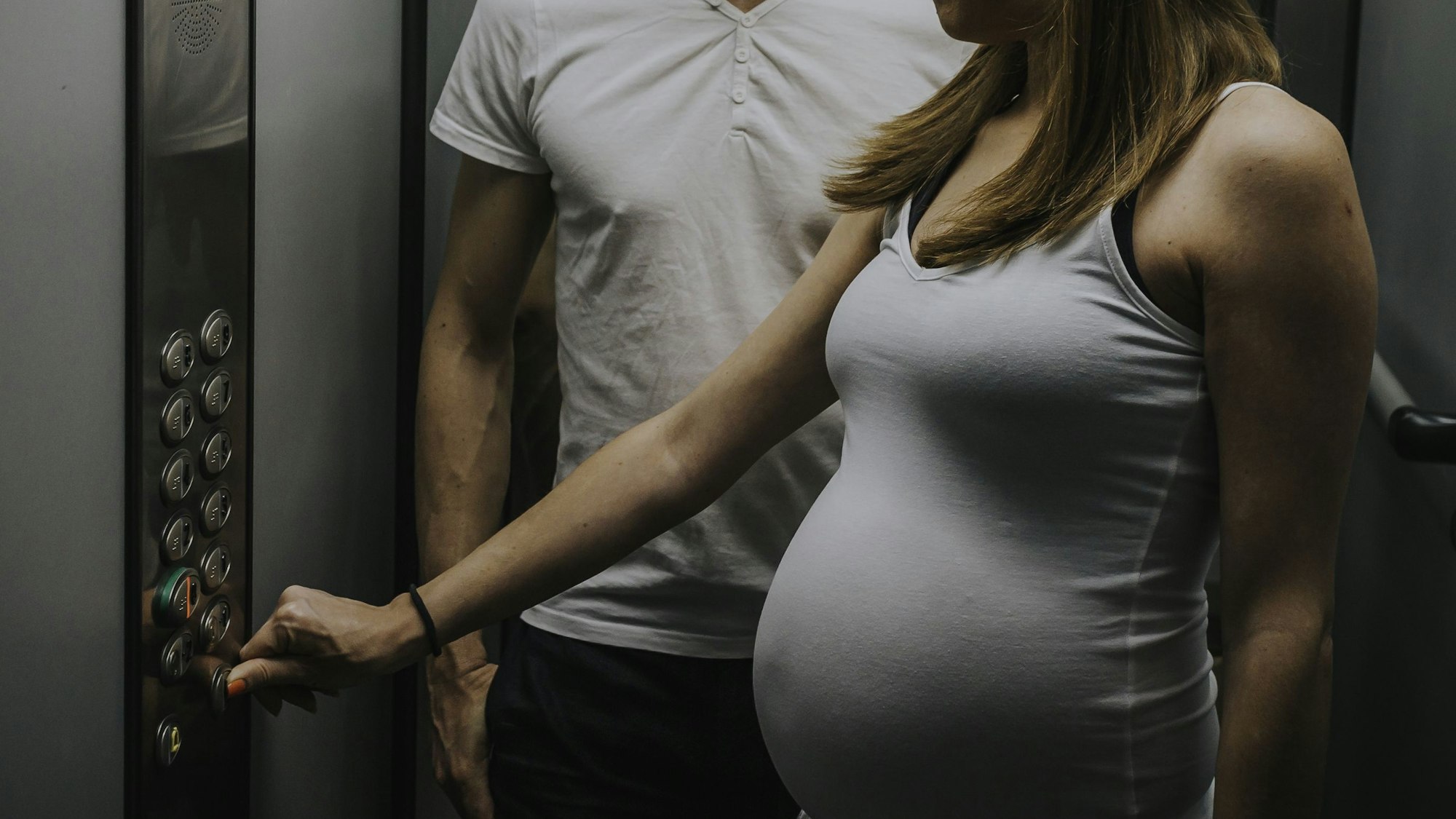Ein Mann und eine schwangere Frau im Aufzug.