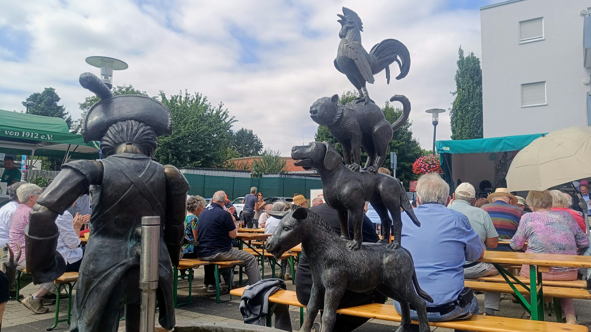 Das Foto zeigt voll besetzte Bänke hinter dem Brunnen beim Brunnenfest.