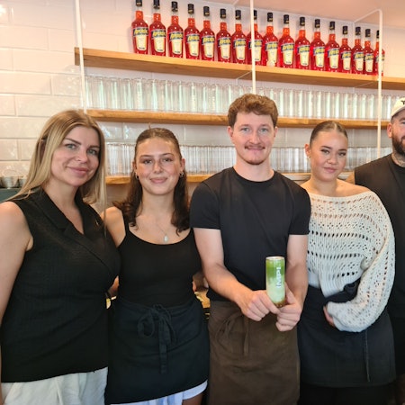 Fünf Menschen stehen nebeneinander hinter der Theke in einem Café.