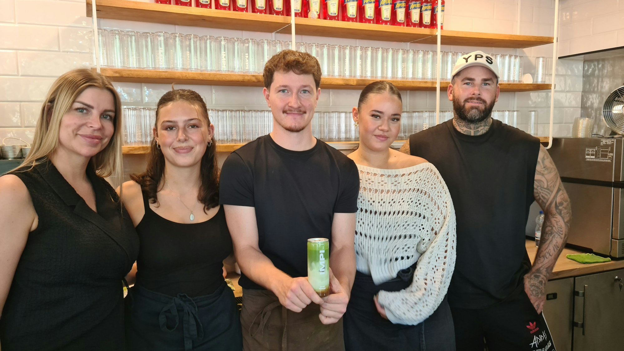 Fünf Menschen stehen nebeneinander hinter der Theke in einem Café.
