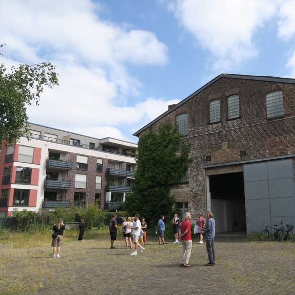 Eine Gruppe Menschen steht vor reiner riesigen Backstein-Halle.