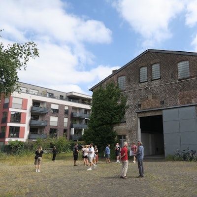 Eine Gruppe Menschen steht vor reiner riesigen Backstein-Halle.