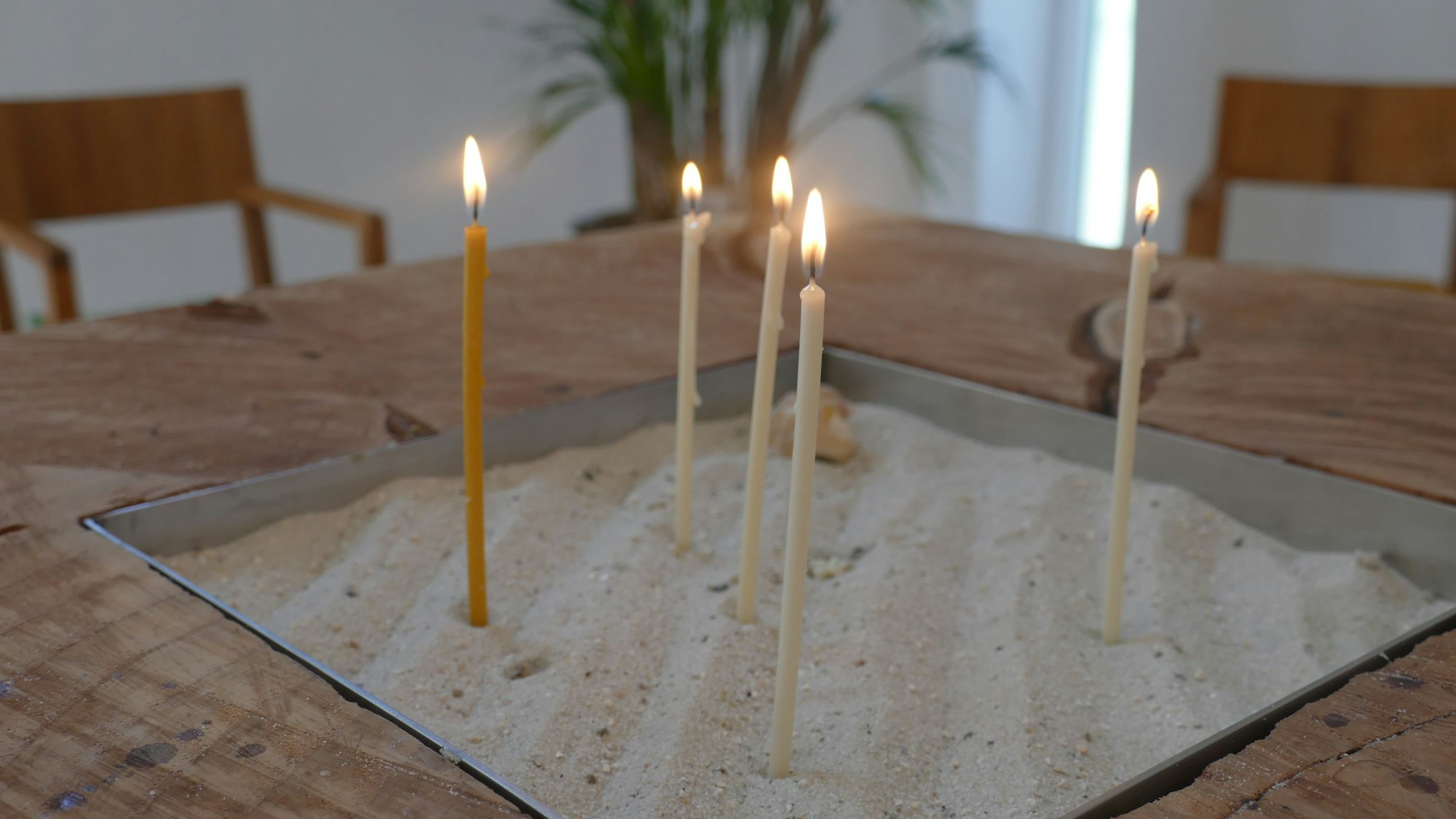 Kerzen brennen in einer mit Sand gefüllten Schale.