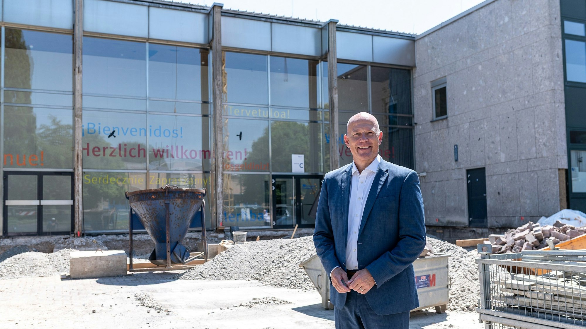 Das Foto zeigt Landrat Frank Rock auf der Baustelle vor der Glasfassade am Eingang des Berufskollegs.