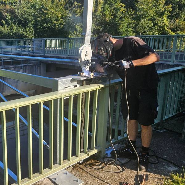 Ein Metallbauer arbeitet an einer Konstruktion an einem Wehr in der Erft.