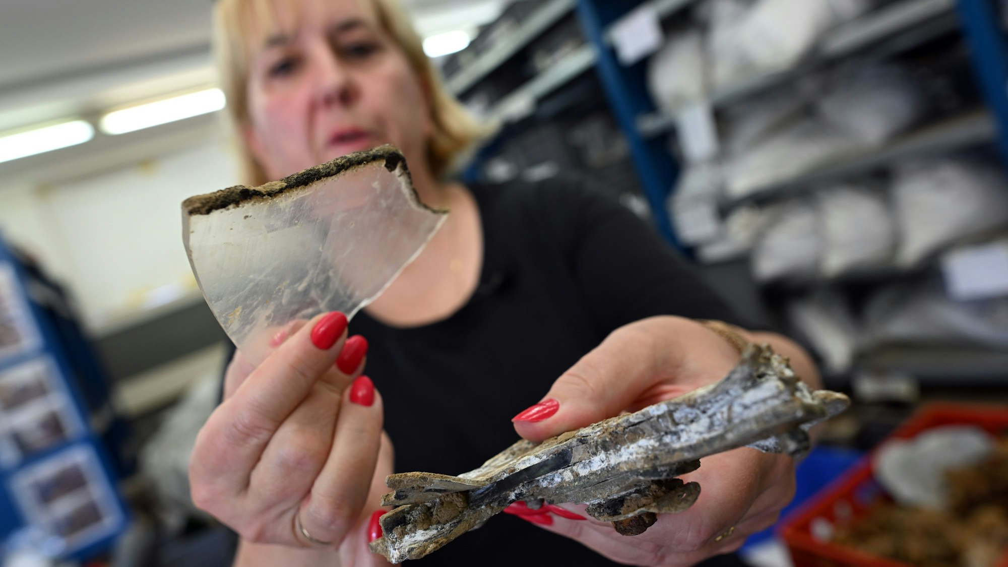 Das Foto zeigt eine Frau, die Plexiglas und Trümmer in die Kamera zeigt.