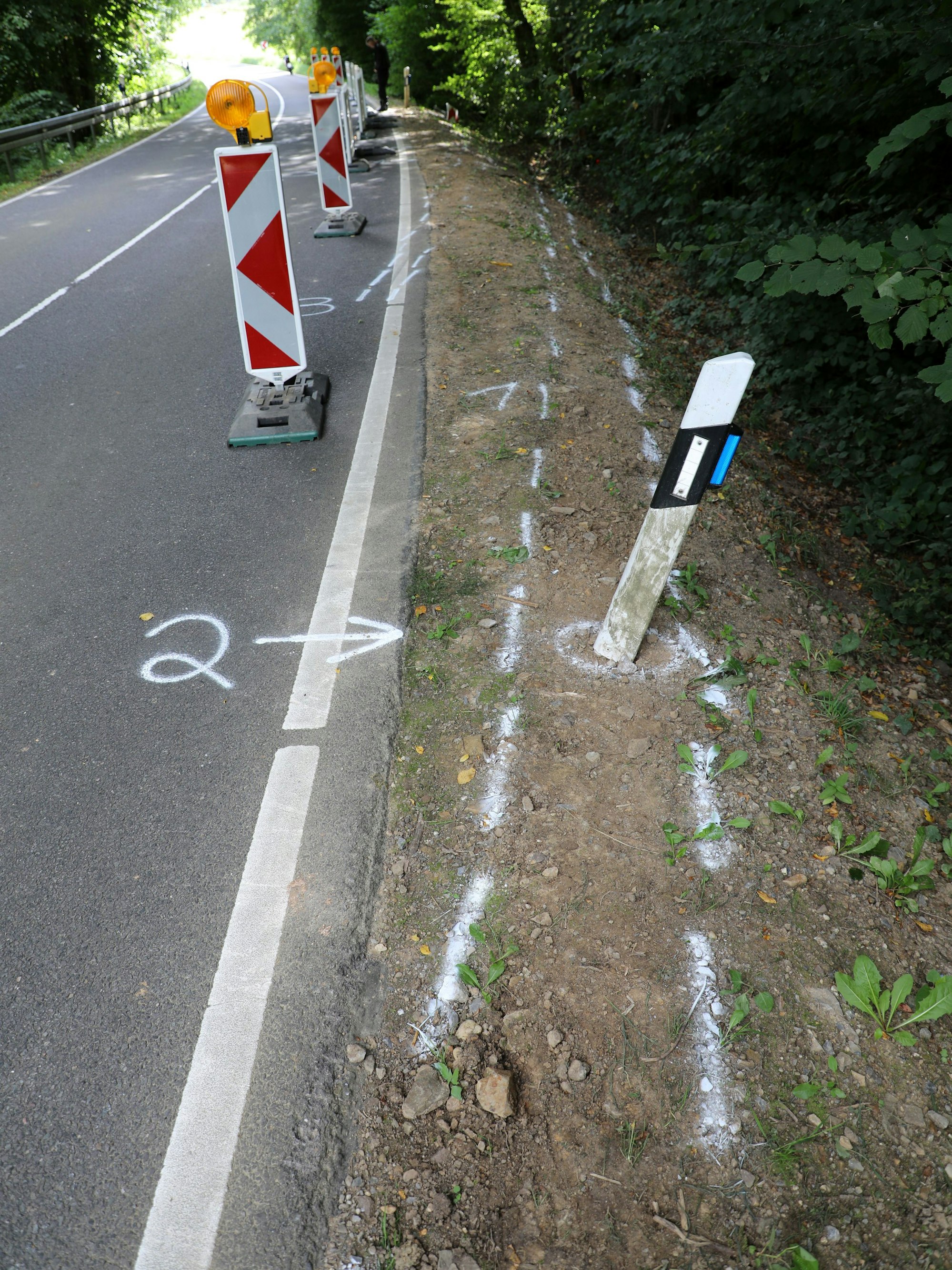 Sprühkreidemarkierungen der Polizei zeigen Unfallspuren im Dürschtal bei Kürten-Dürscheid.