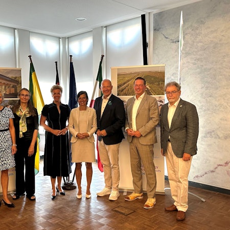 Frauen und Männer stehe nebeneinander und lächeln.