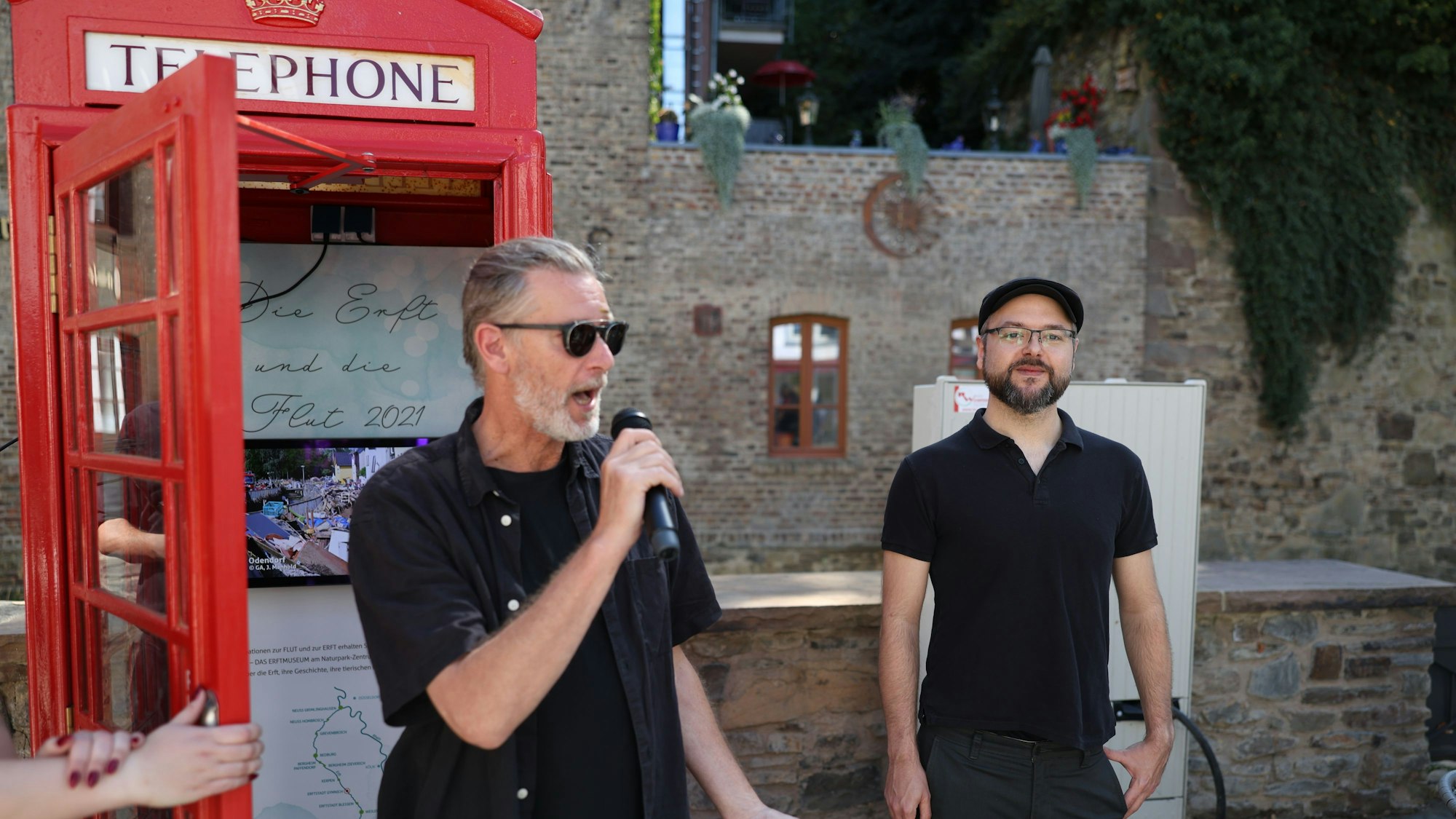 Die beiden Fotografen bei einer Ansprache zur Eröffnung der neuen roten Telefonzelle.