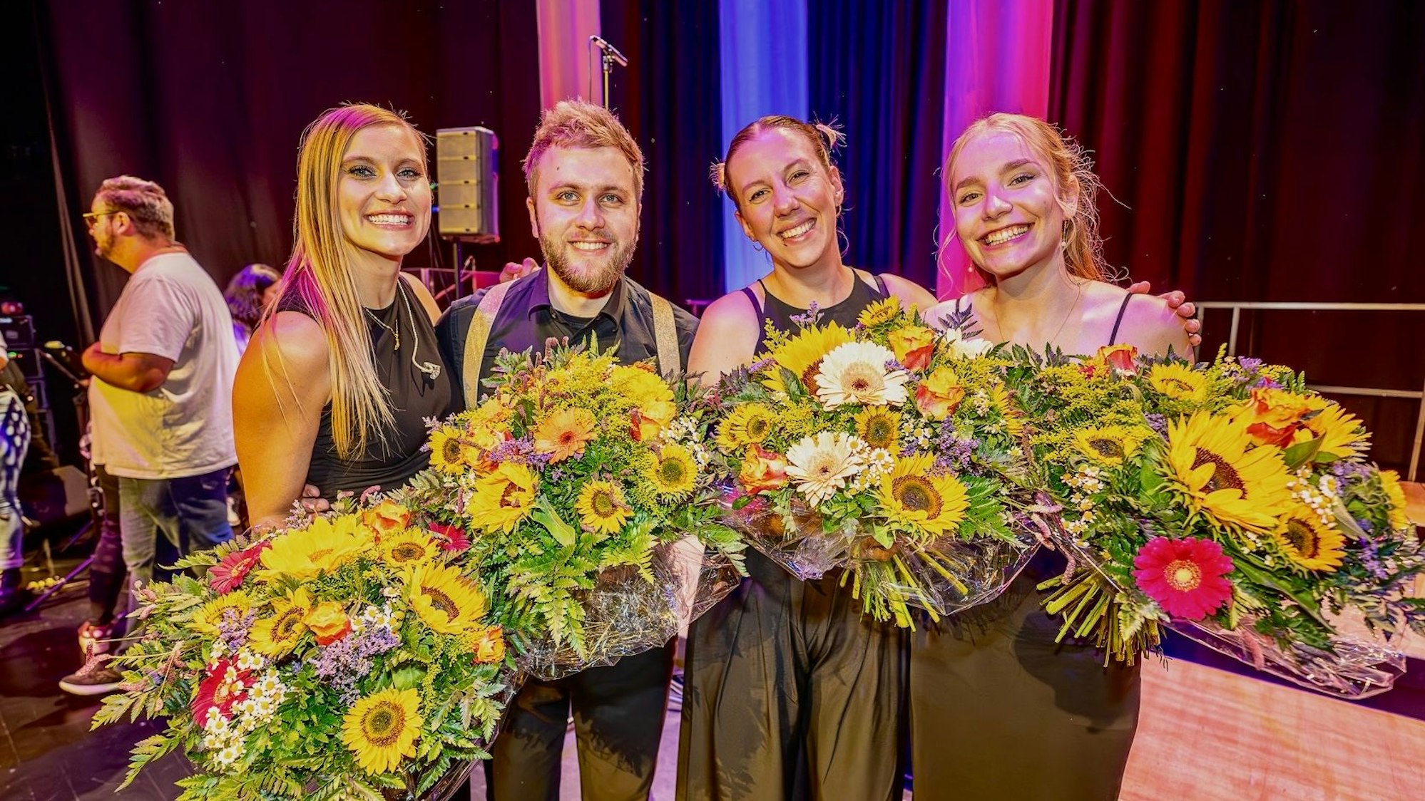 Das Bild zeigt die vier Chorleiter, sie halten Blumensträuße in den Händen und sind elegant gekleidet.