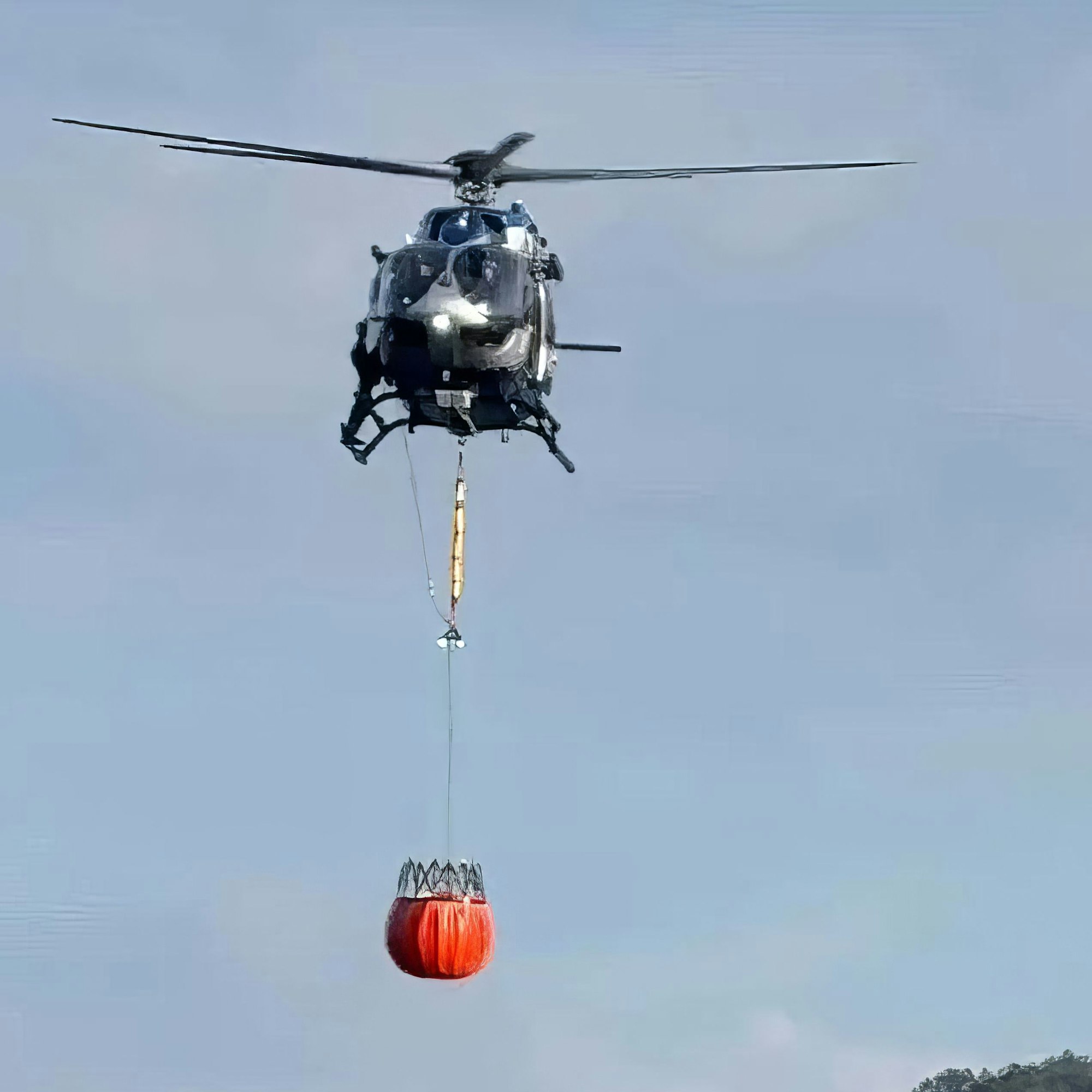Ein Polizeihubschrauber mit angehängtem Bambi Bucket bei der Wasseraufnahme am Rursee in Schwammenauel.