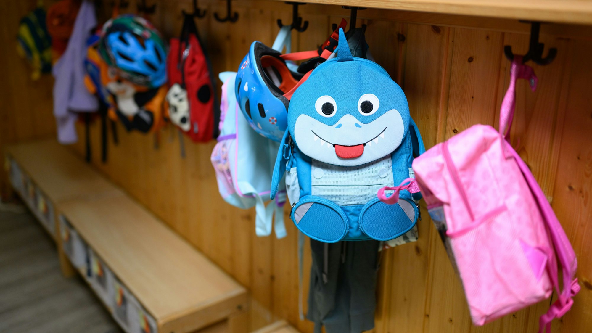 Kinderrucksäcke hängen in der Garderobe einer Kita.