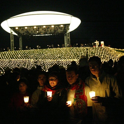 Pilger halten vor dem Papsthügel auf dem Marienfeld bei Kerpen Kerzen in der Hand.