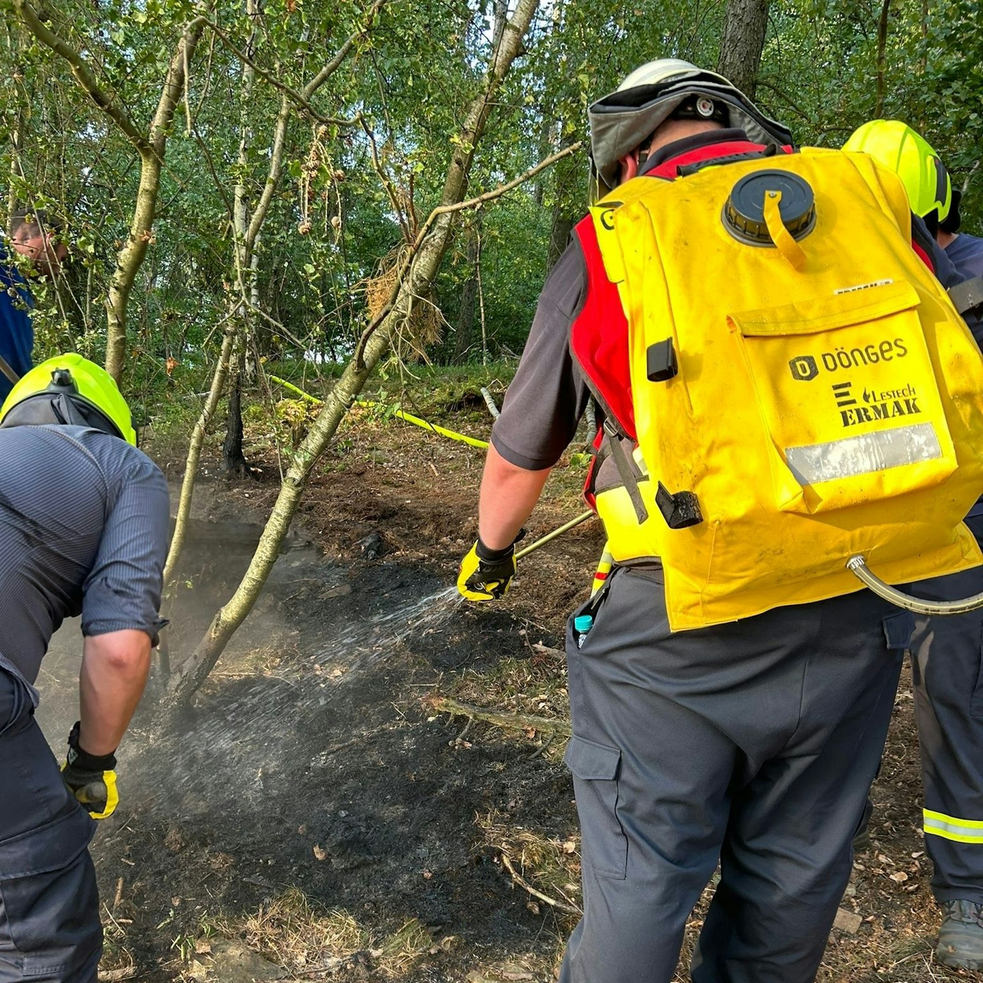 Ein Feuerwehrmann trägt einen gelben Löschrucksack bei einem Einsatz im Nationalpark Eifel.