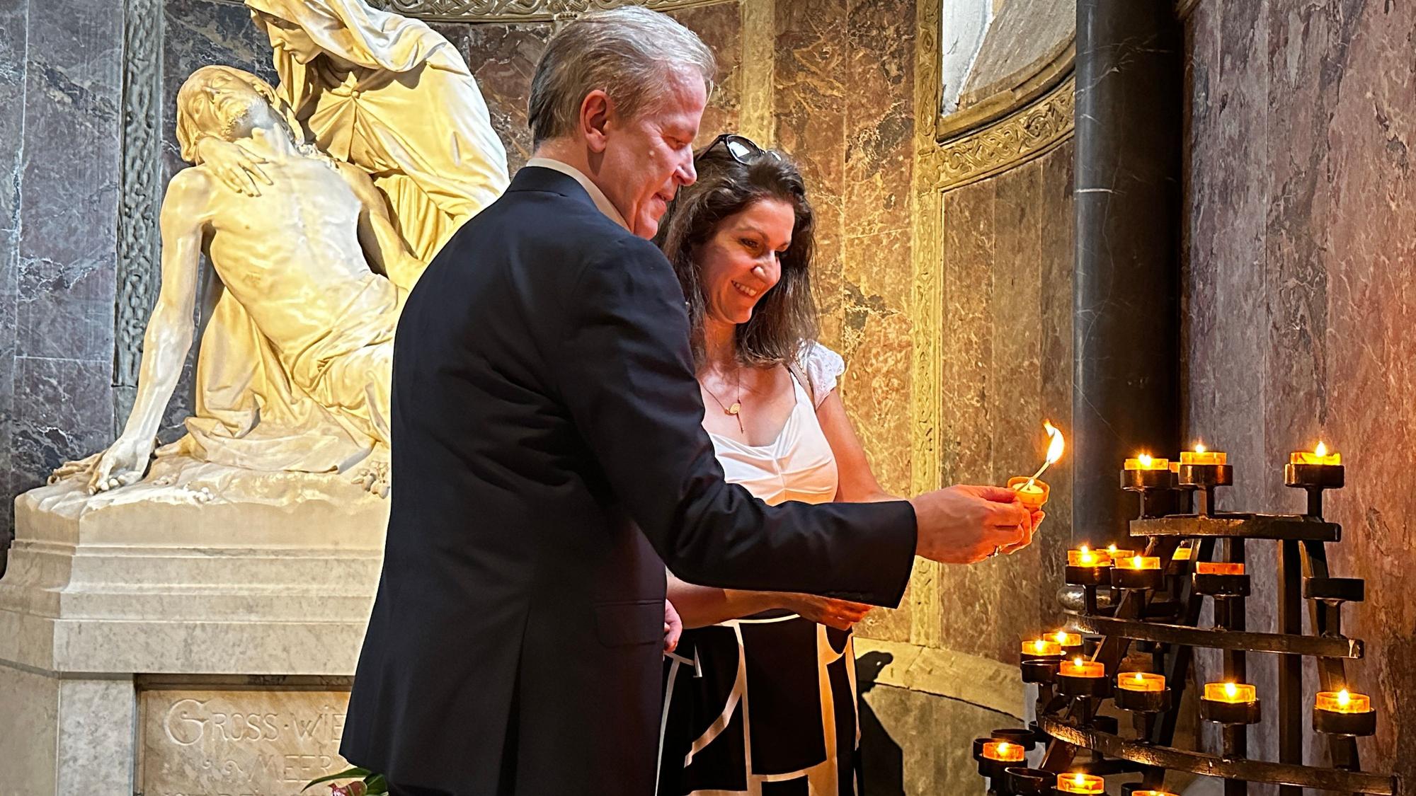 Eine Frau und ein Mann zünden Kerzen in einer Kirche an.