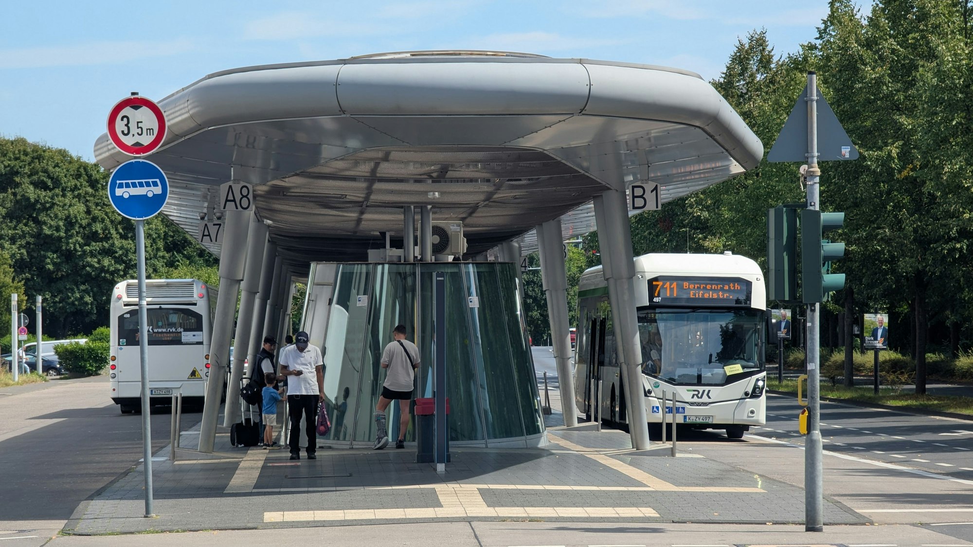 Das Foto zeigt zwei Busse und wartende Fahrgäste am Busbahnhof in Hürth-Mitte.